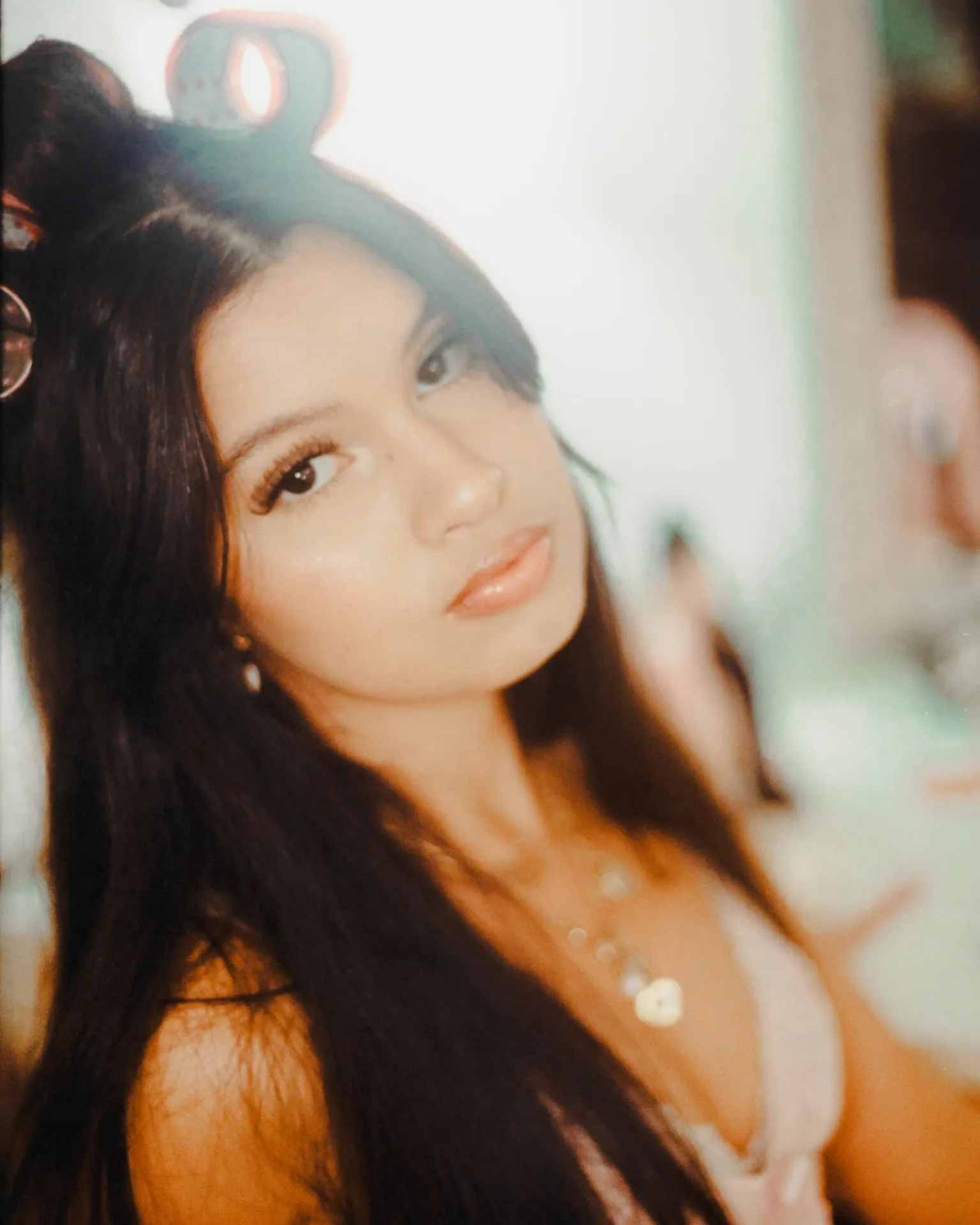 Close editorial portrait with hair curlers and glossy makeup on CineStill 400D film