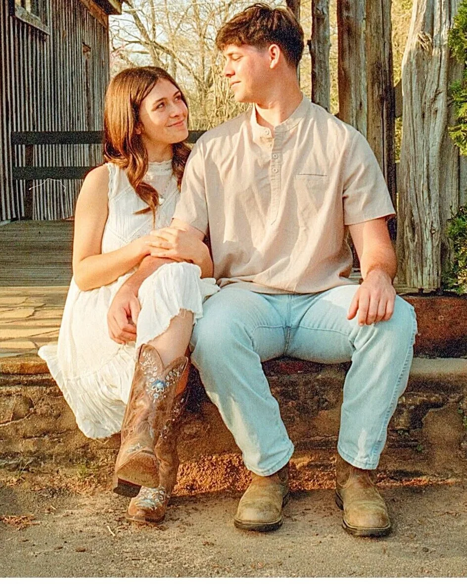 Couple sitting together on a porch in boots during a film engagement session