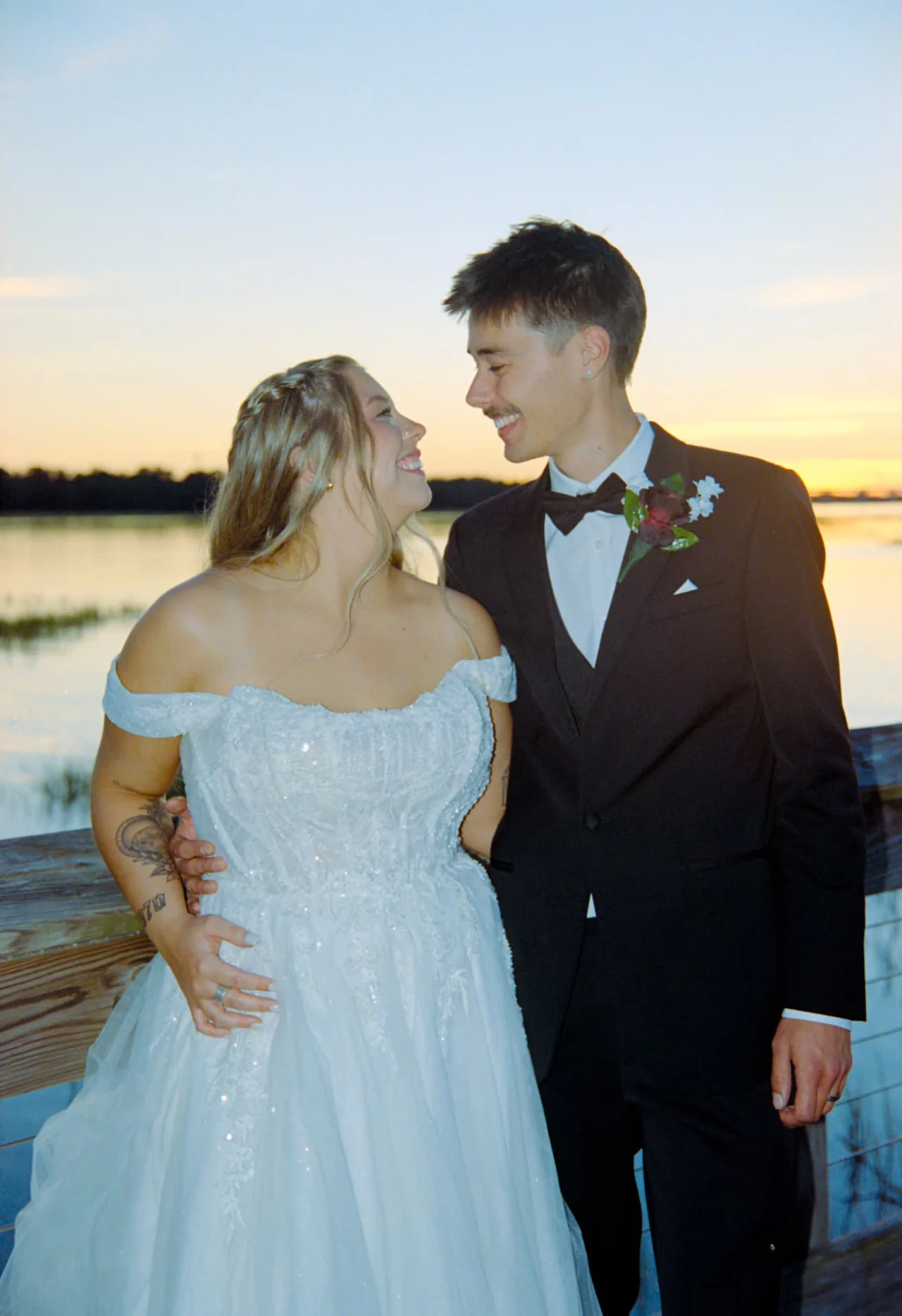 Newlyweds embracing on a wooden dock at sunset, photographed on Portra 400 wedding film