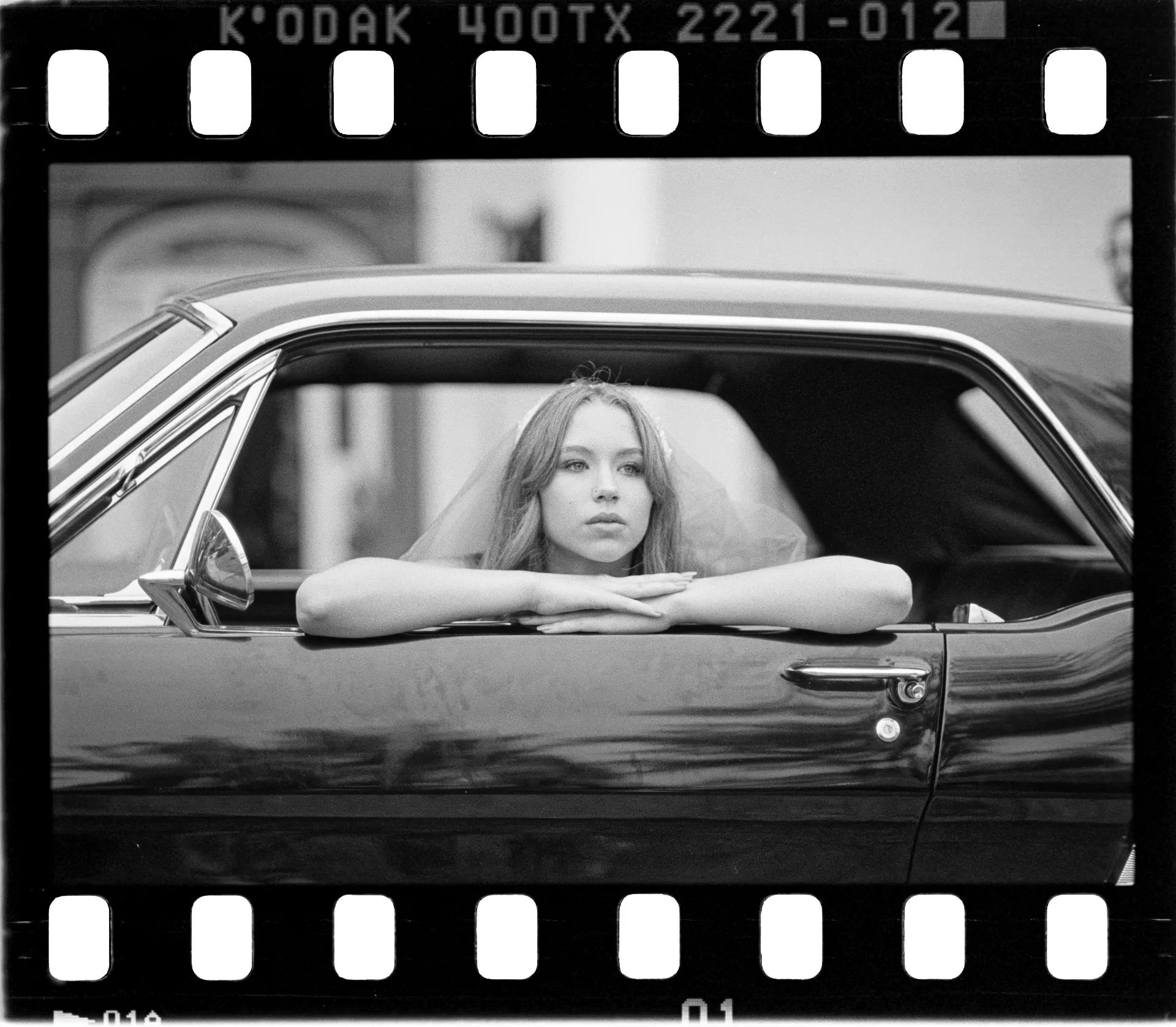 Bride and groom laughing in a vintage car, shot on 35mm film