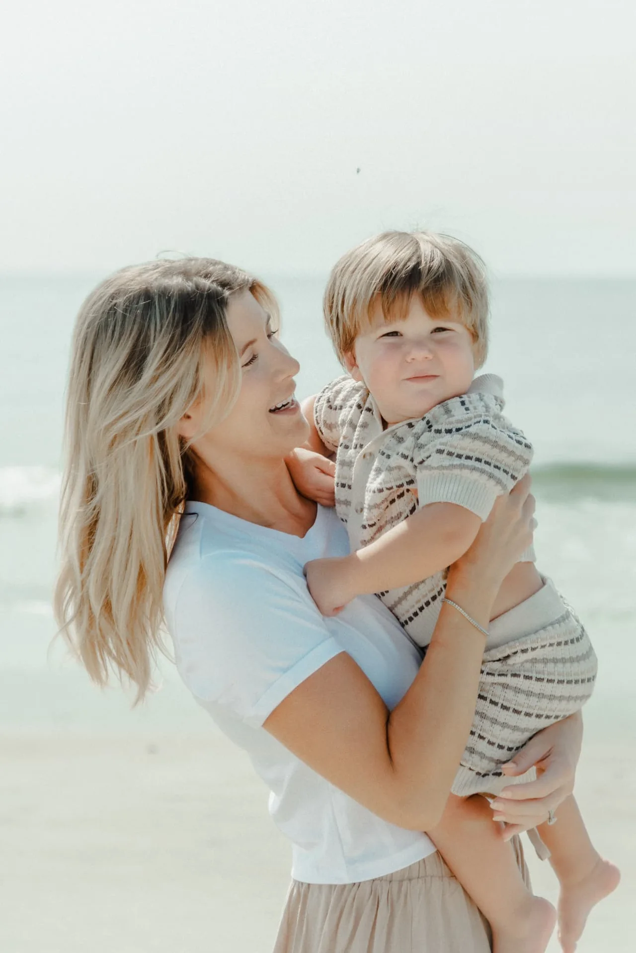 Mother holding her young child beside the ocean