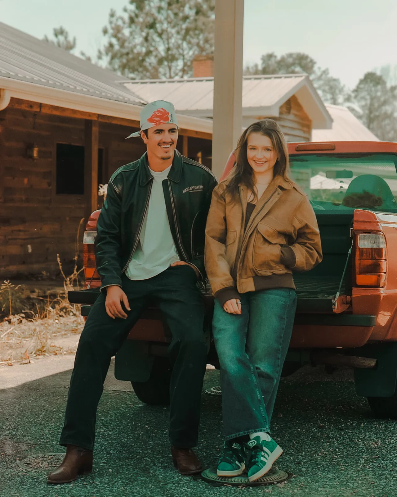 Couple sitting on the tailgate of a vintage red truck during an editorial engagement session on CineStill 400D film