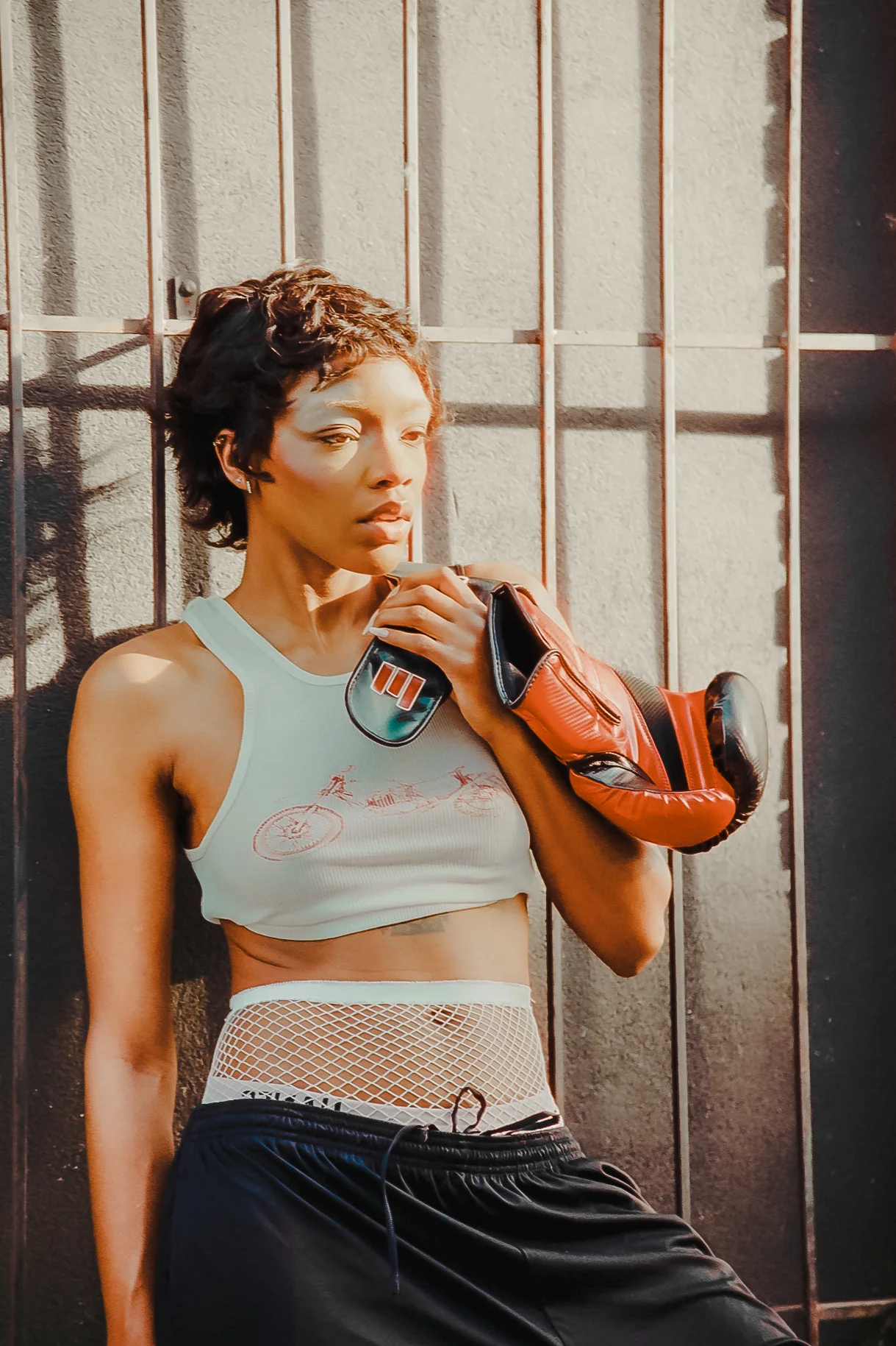 Editorial portrait with red boxing gloves and a graphic tank top in hard window light on CineStill 400D film