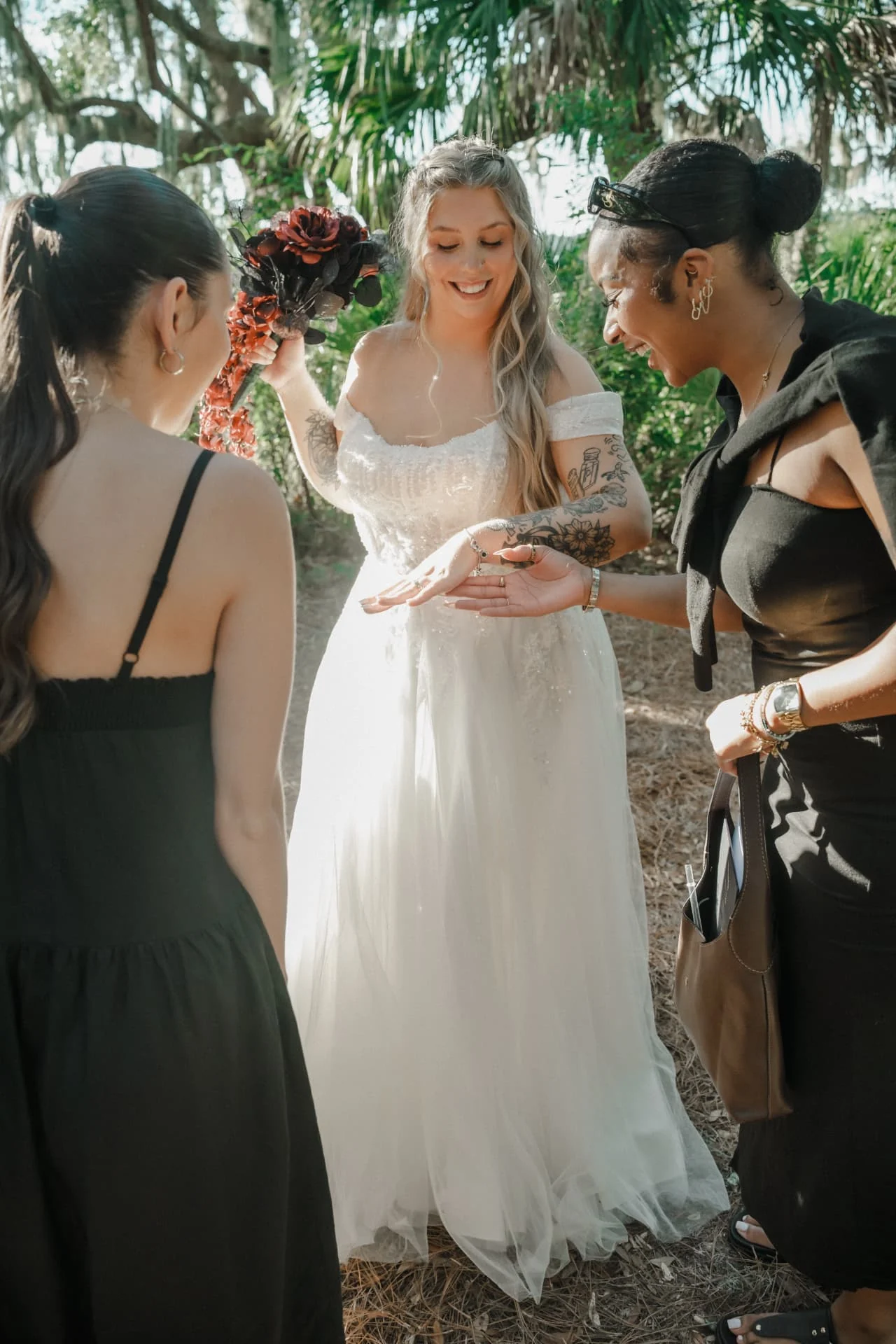 Bride sharing her wedding ring with friends beneath palmetto leaves