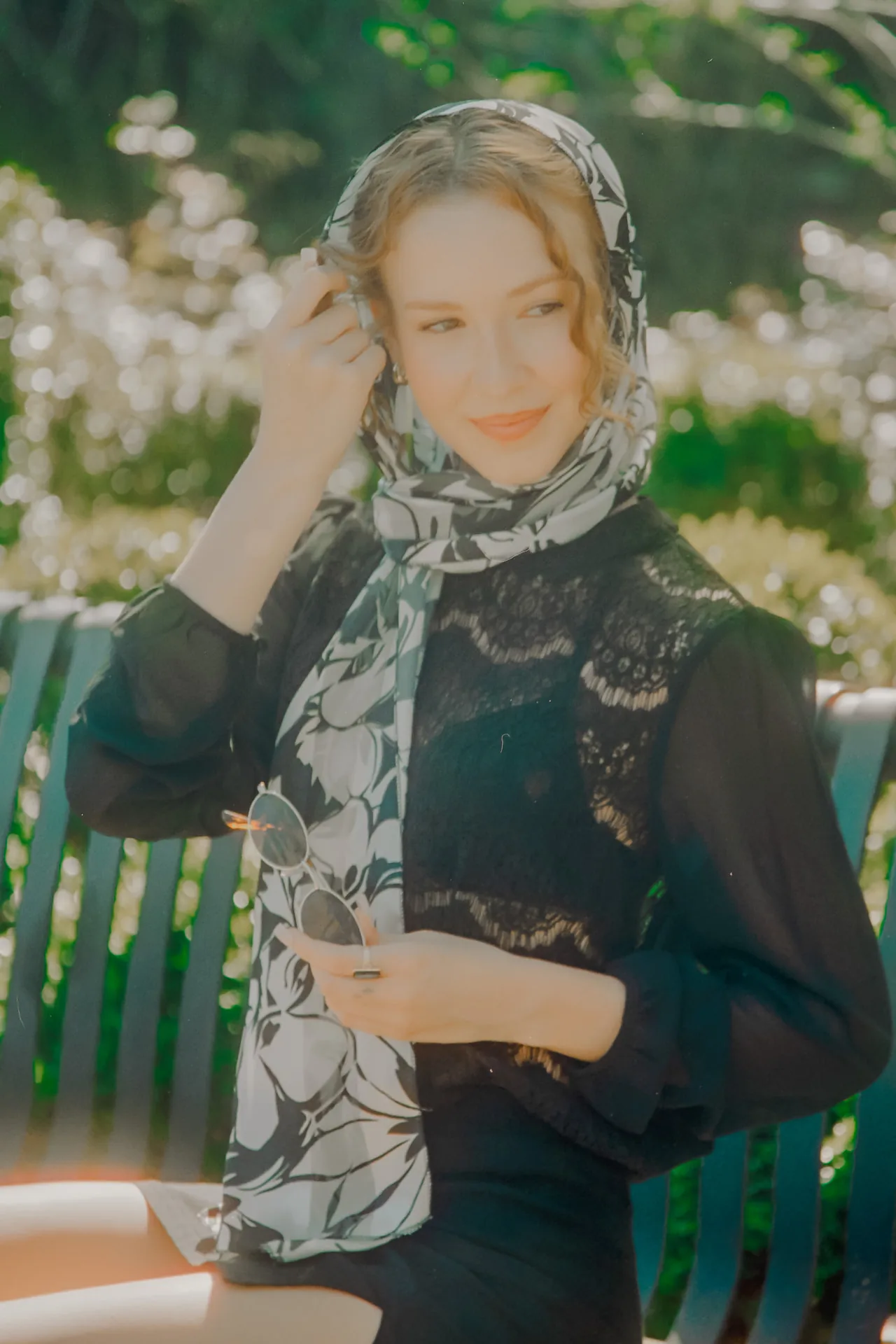 Editorial portrait with a floral headscarf on a park bench photographed on CineStill 400D film