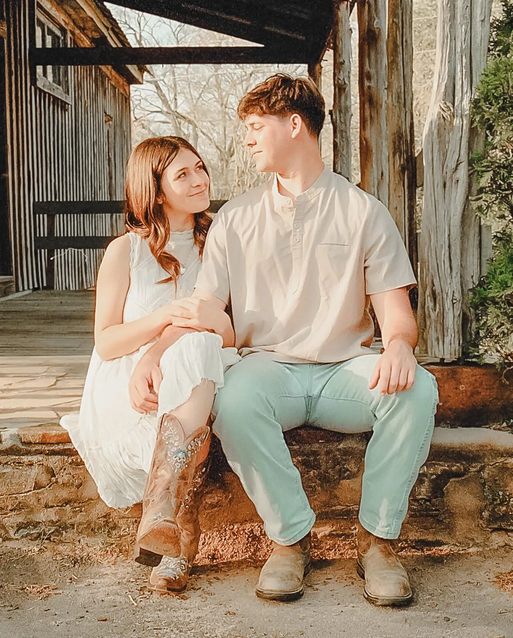 Couple sitting together on a porch in boots during a film engagement session