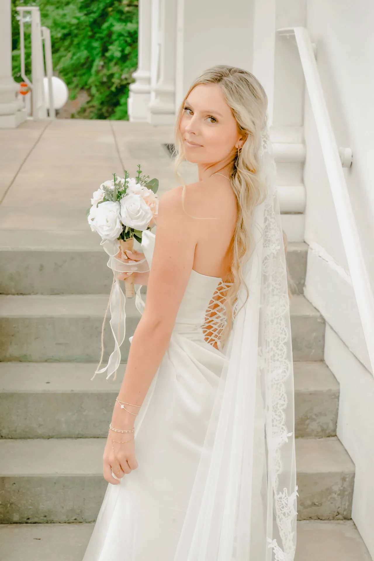 Blonde bride in a veil standing on steps for a digital wedding portrait