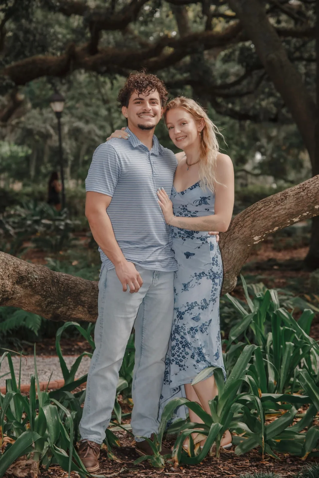 Engaged couple standing together beneath a sprawling live oak in Savannah