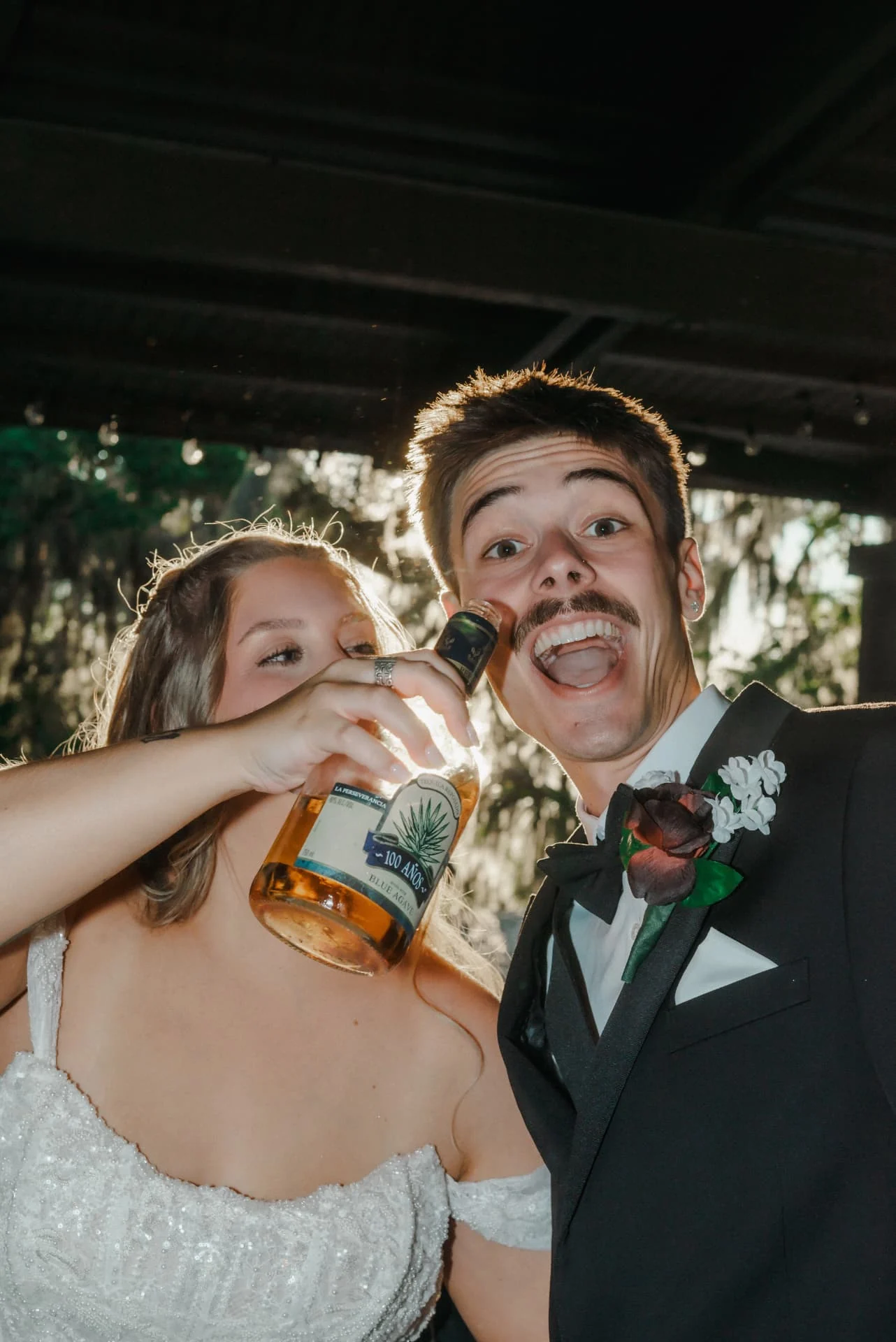 Newlyweds laughing and celebrating together beneath a wooden pavilion