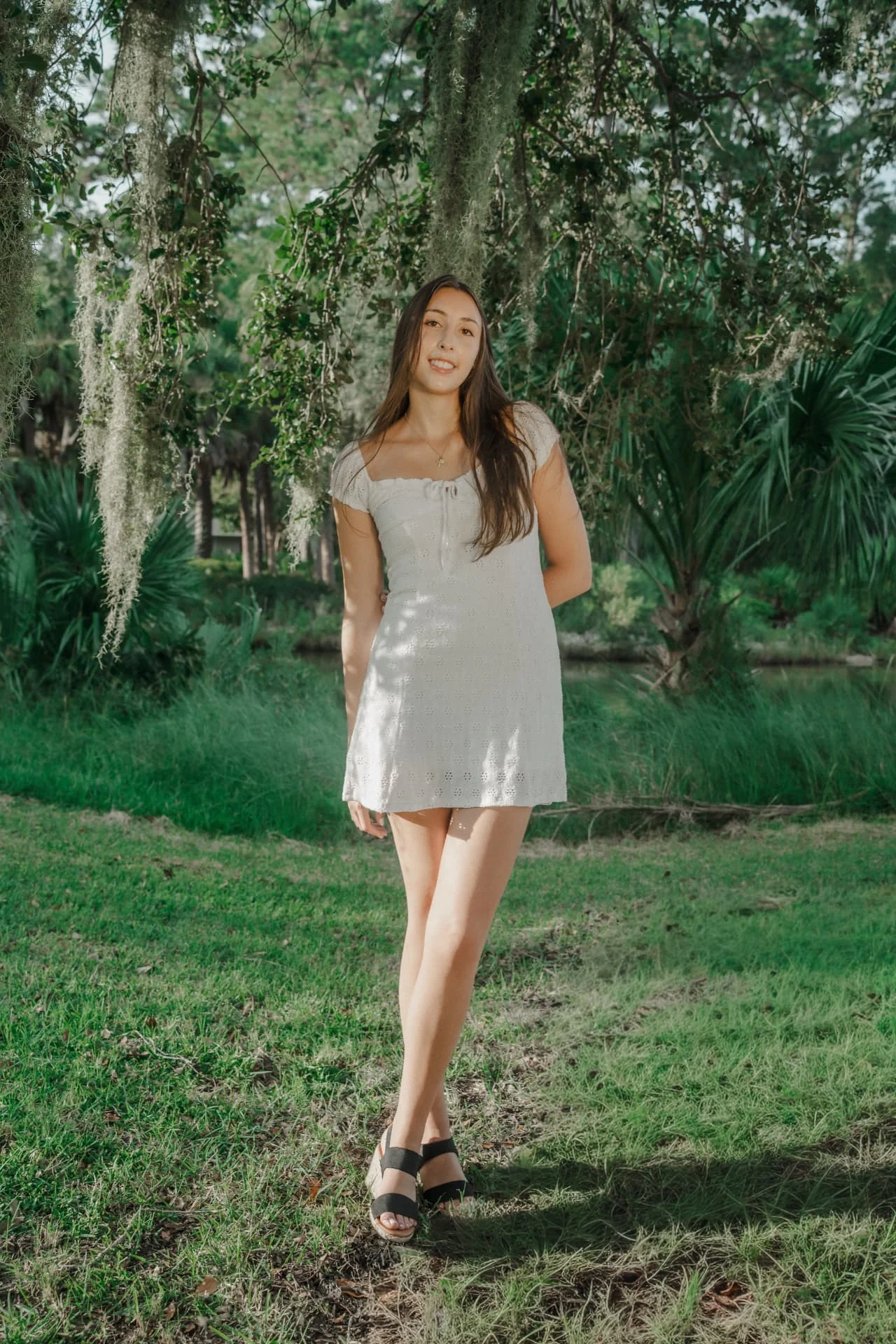 Full-length portrait of a sister in a white dress beneath Spanish moss