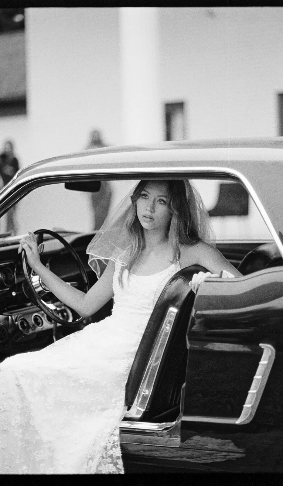 Bride posed by a vintage Mustang in an editorial film wedding portrait