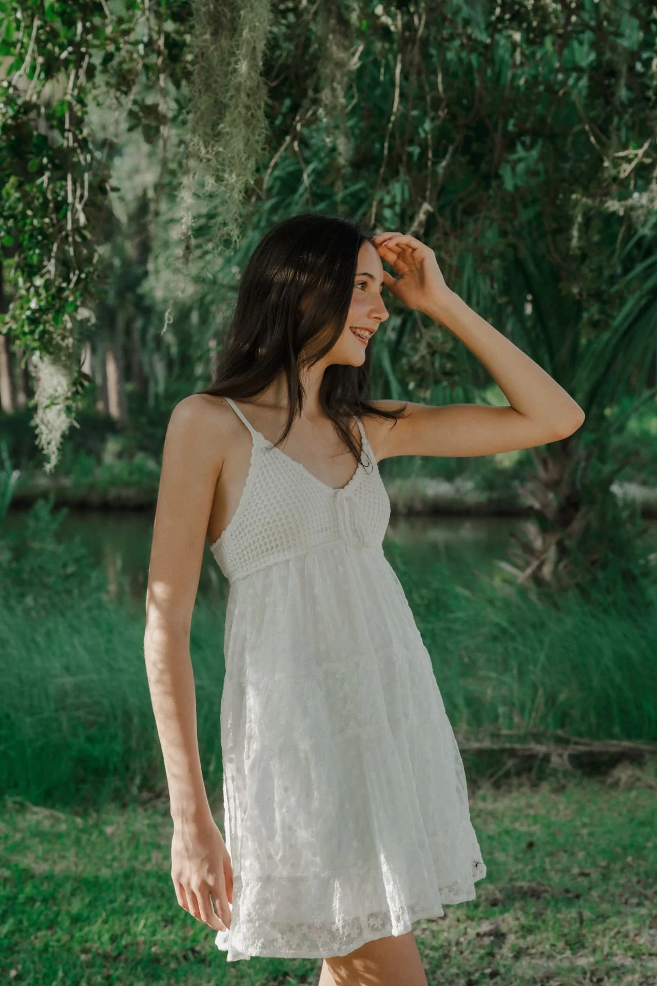 Candid portrait of a sister in a white sundress among the greenery