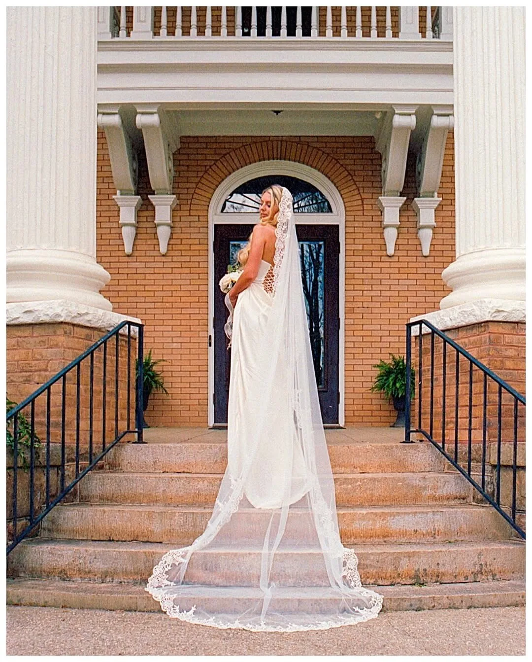 Bride in a veil photographed on stone steps with soft Portra film color