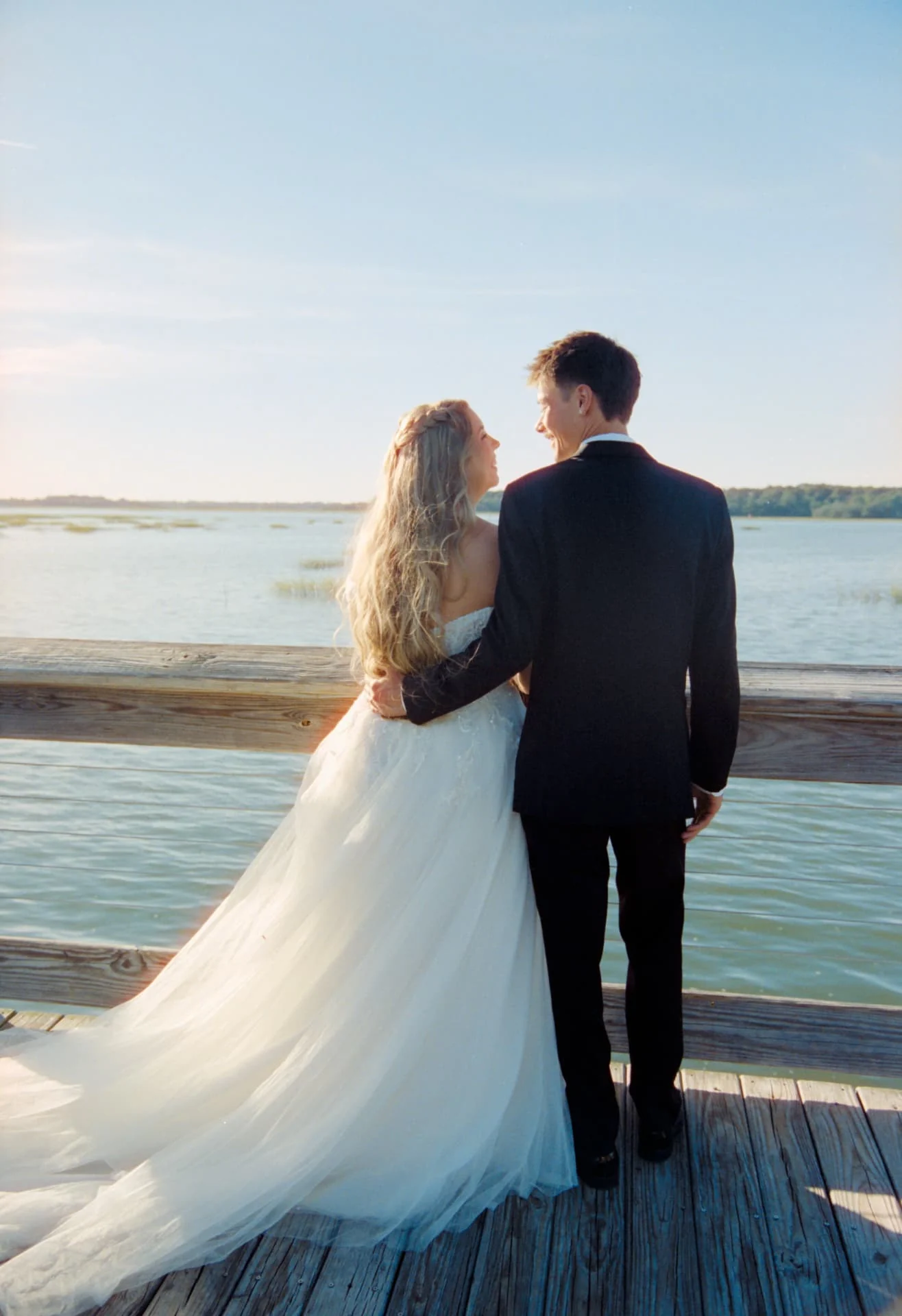 Bride and groom looking at each other at a waterfront railing on CineStill 400D film, Savannah wedding photography