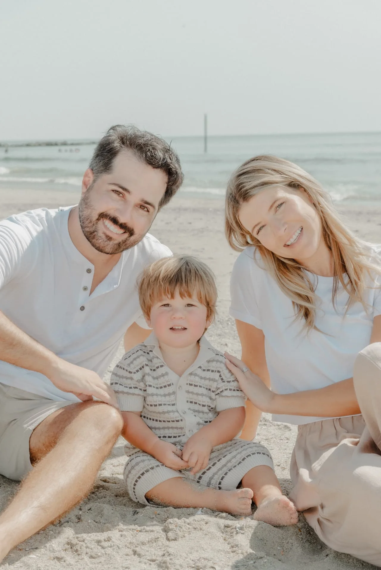 Family of three sitting together on the beach