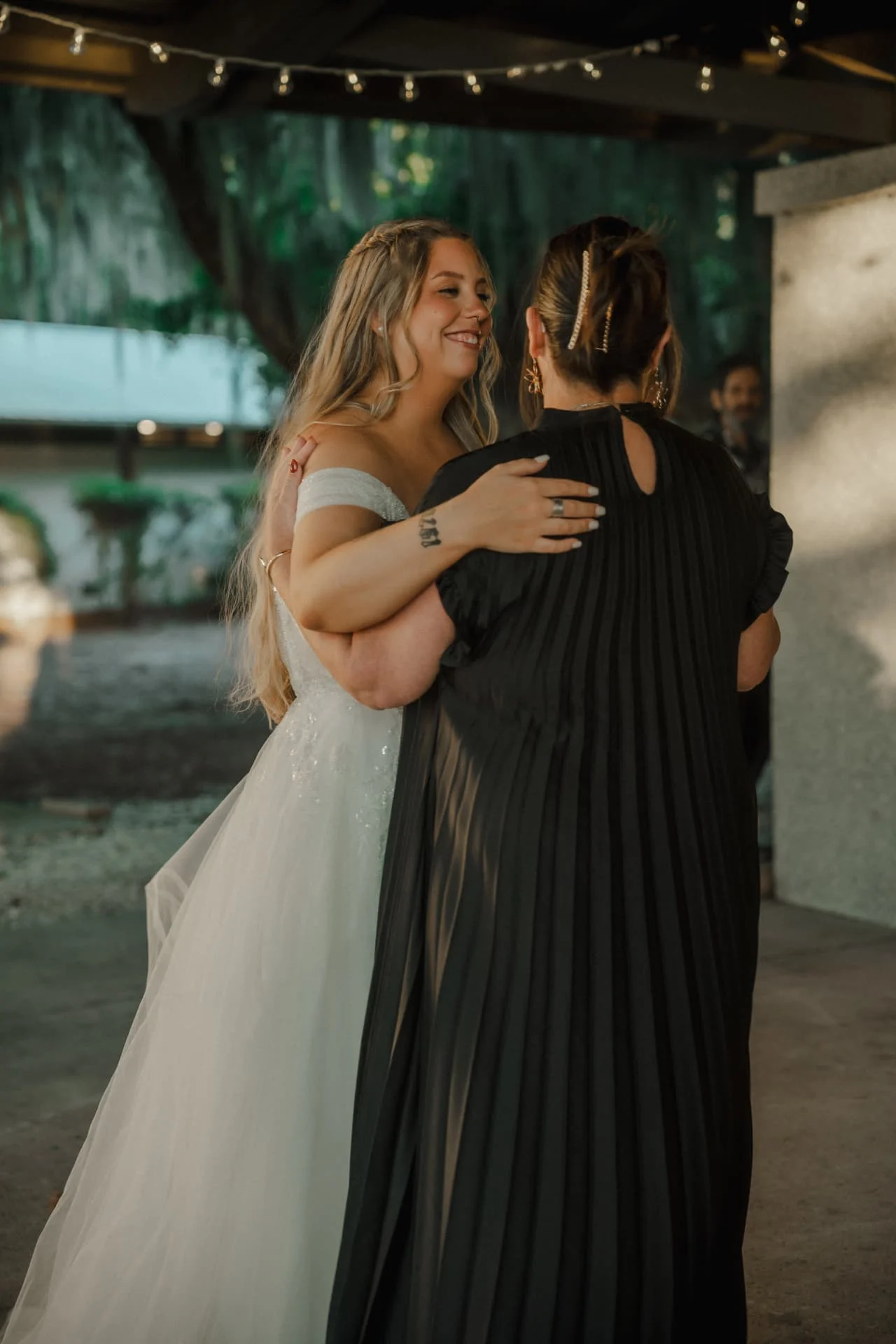 Bride sharing a dance with her mother under the reception string lights