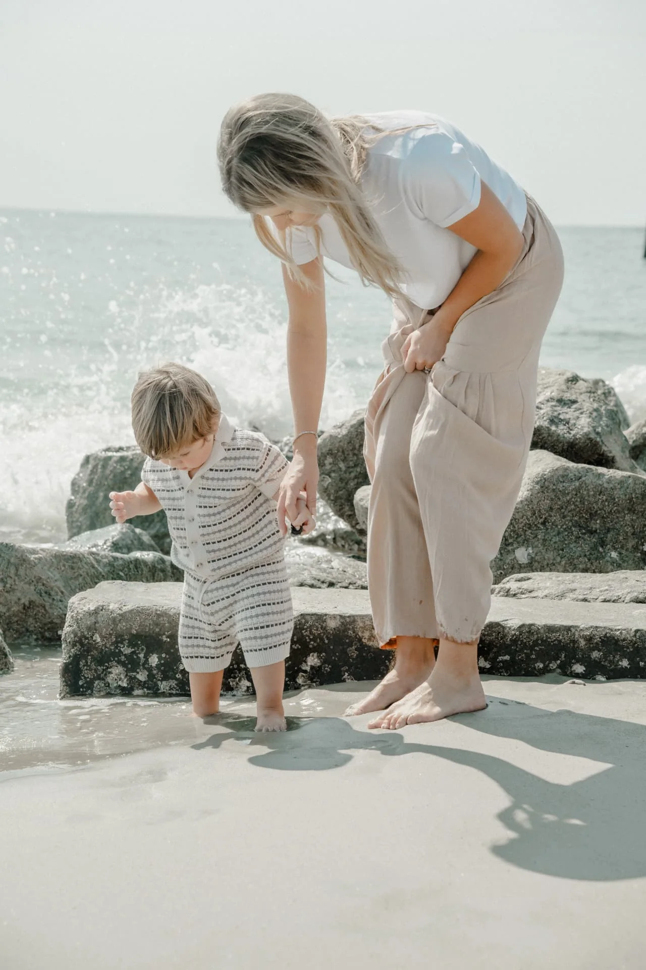 Mother helping her young child explore the shoreline