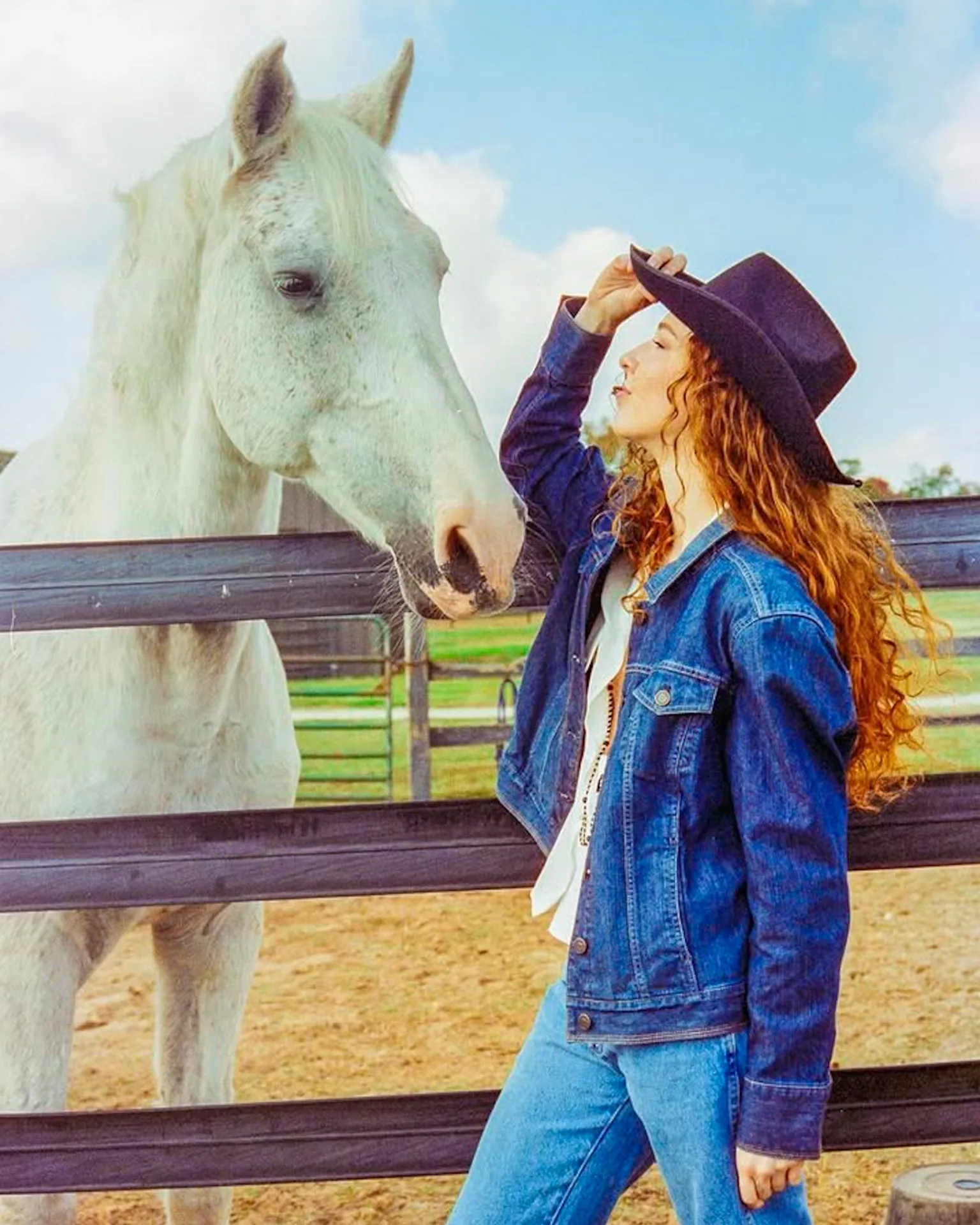 Denim cowgirl editorial portrait beside a horse on CineStill film