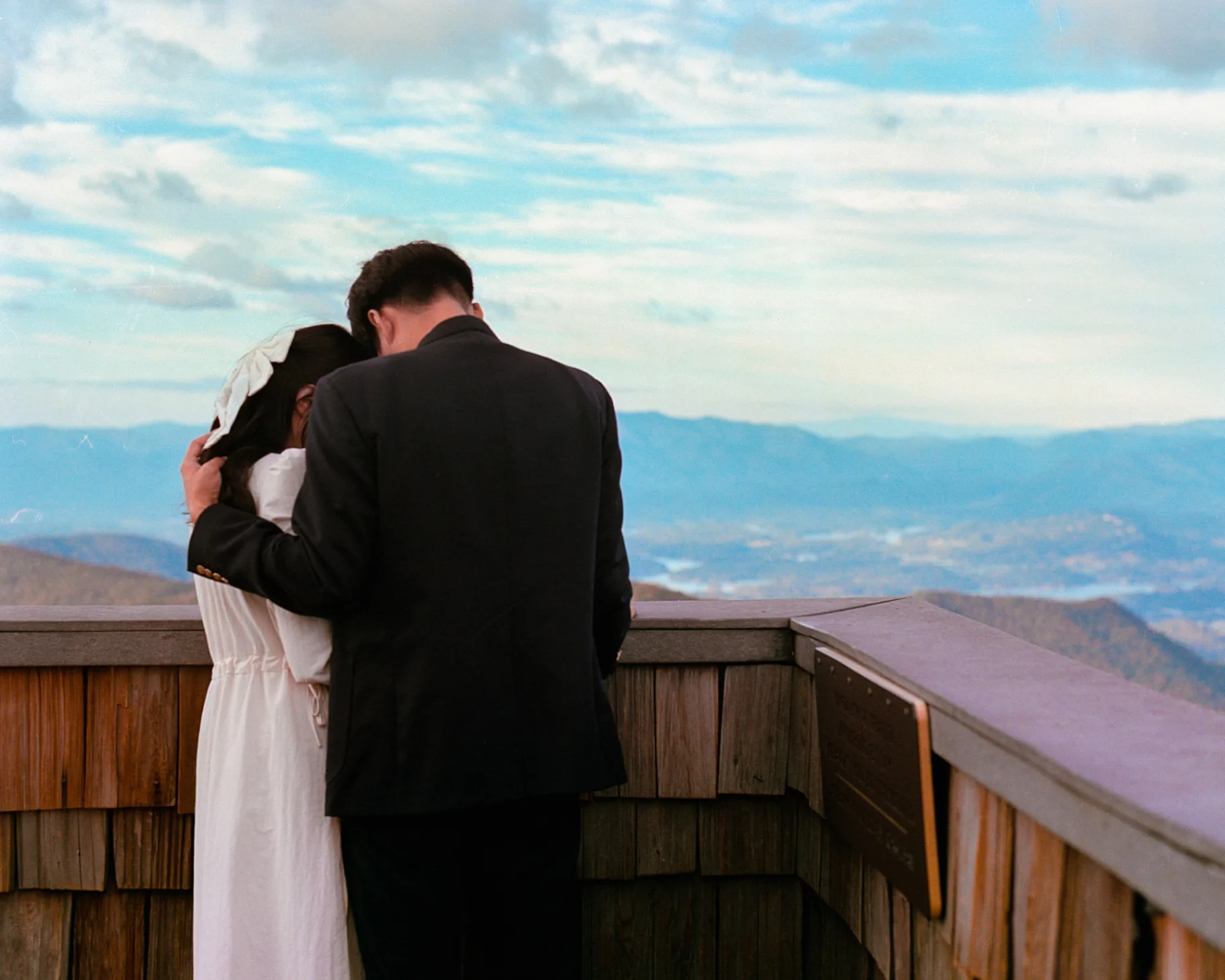 Engaged couple overlooking blue mountains from a wooden balcony