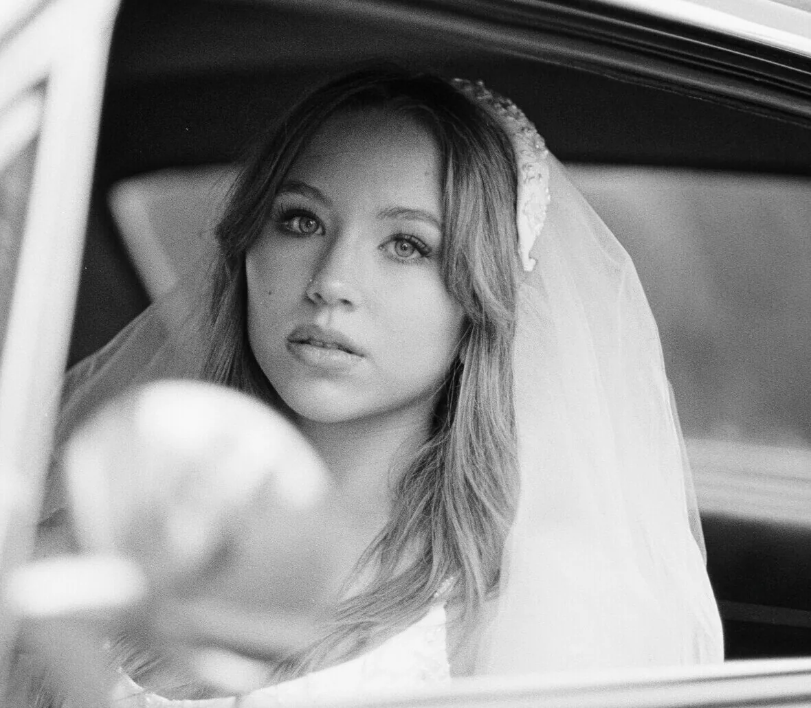 Bride standing near a window in a soft film-inspired wedding portrait