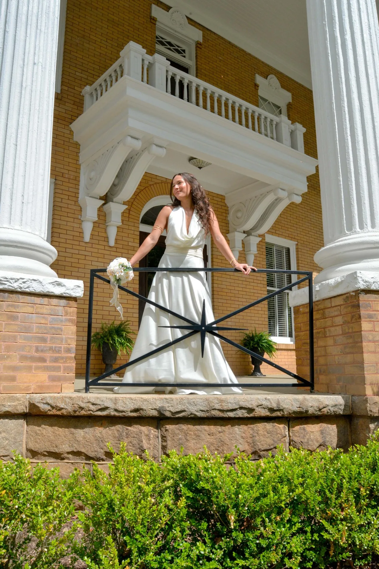 Bride posing by a column railing during an elegant digital wedding session