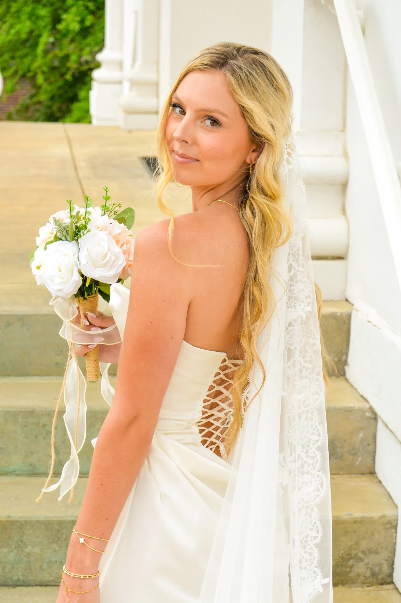 Blonde bride in a veil standing on steps for a digital wedding portrait