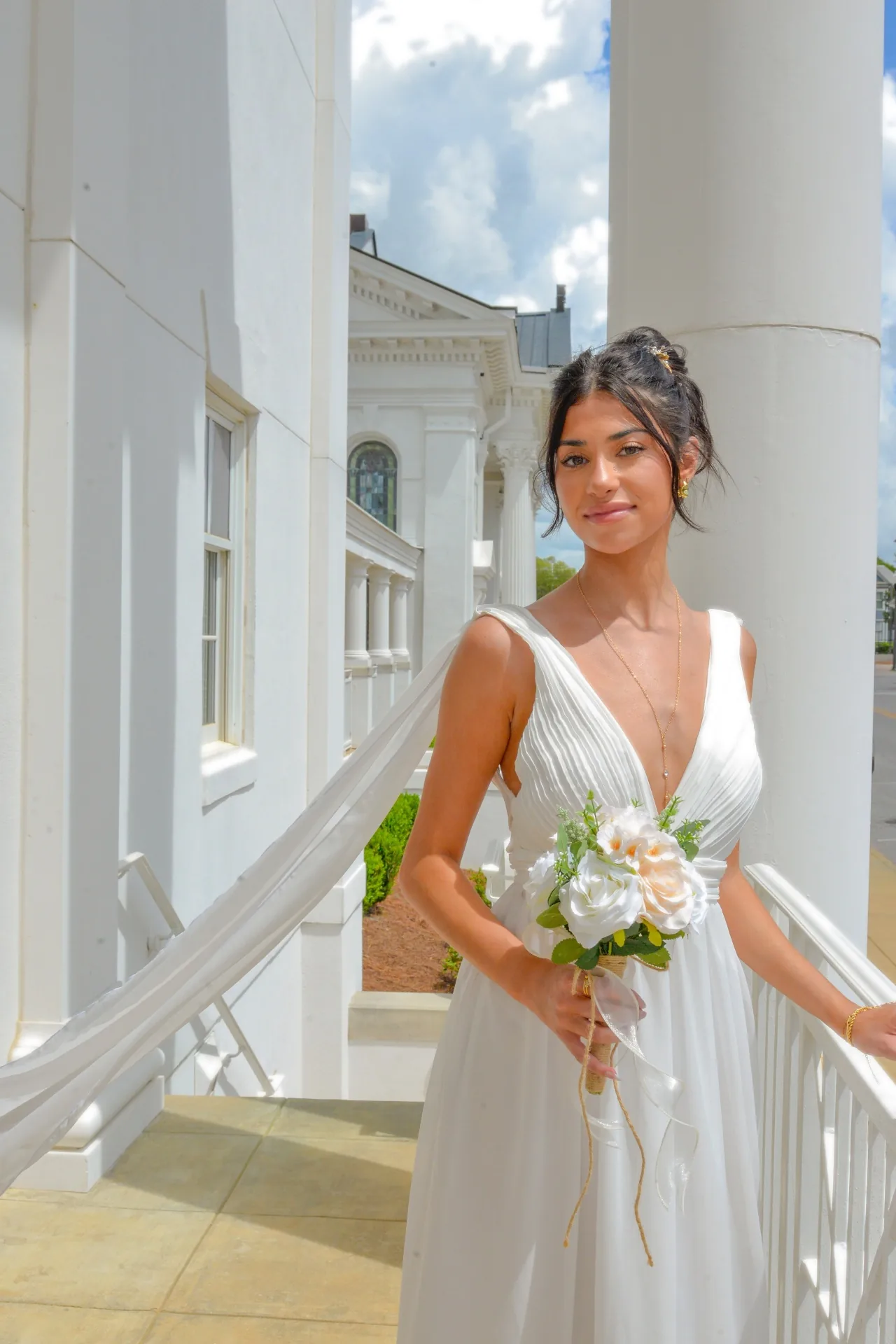 Bride holding her bouquet near white columns in a digital wedding portrait